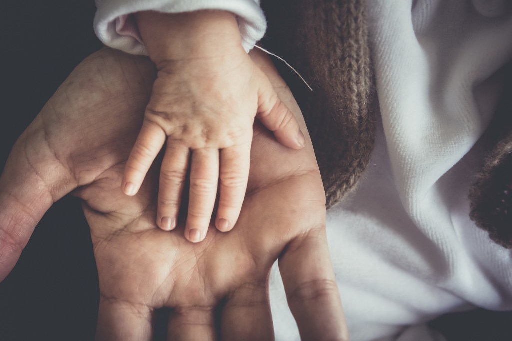 A child’s and adults hand on top of each other