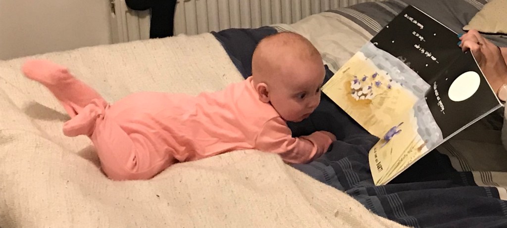A picture of my baby lying on her tummy reading a story.